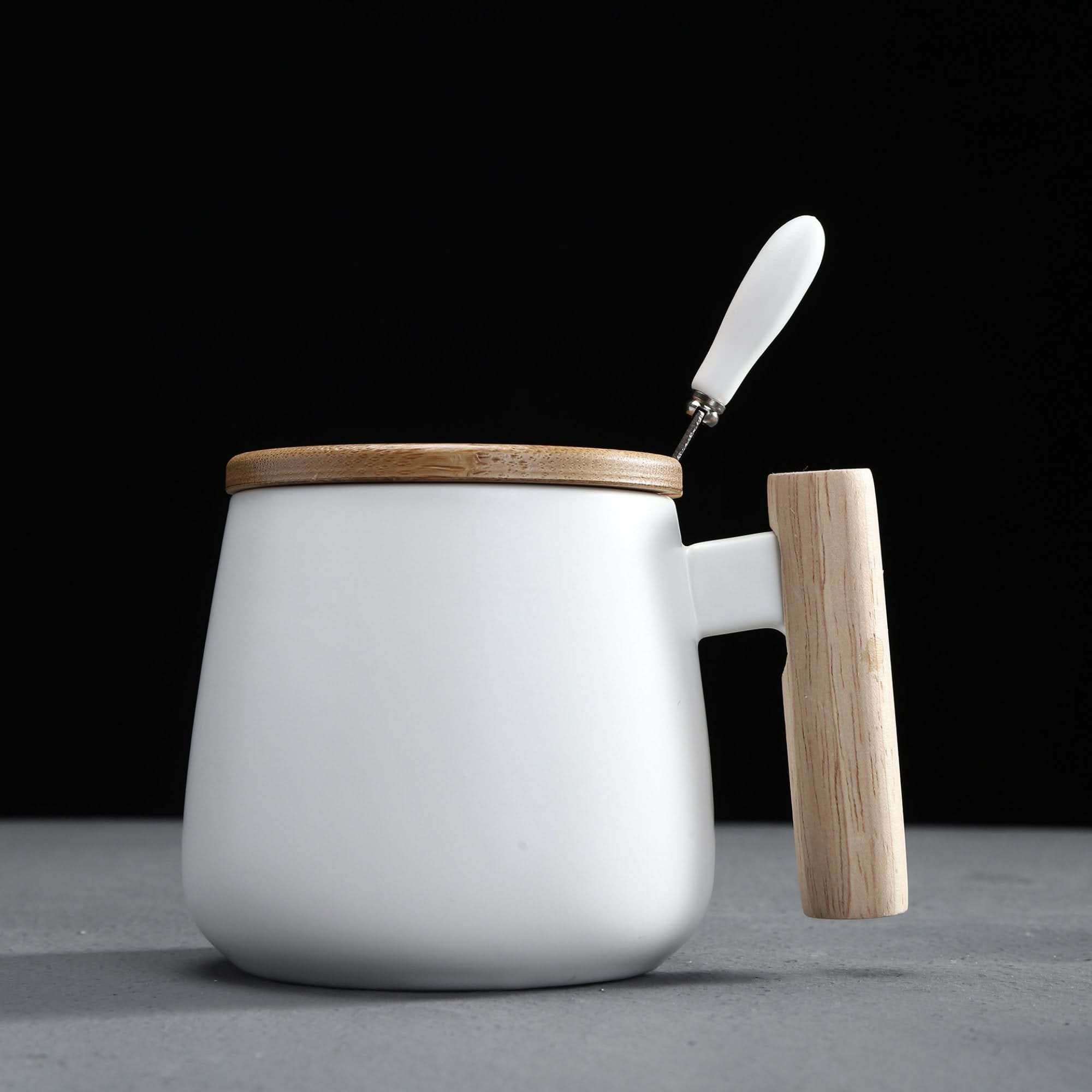 White Japanese style coffee mug with wood handle & lid, on grey surface.
